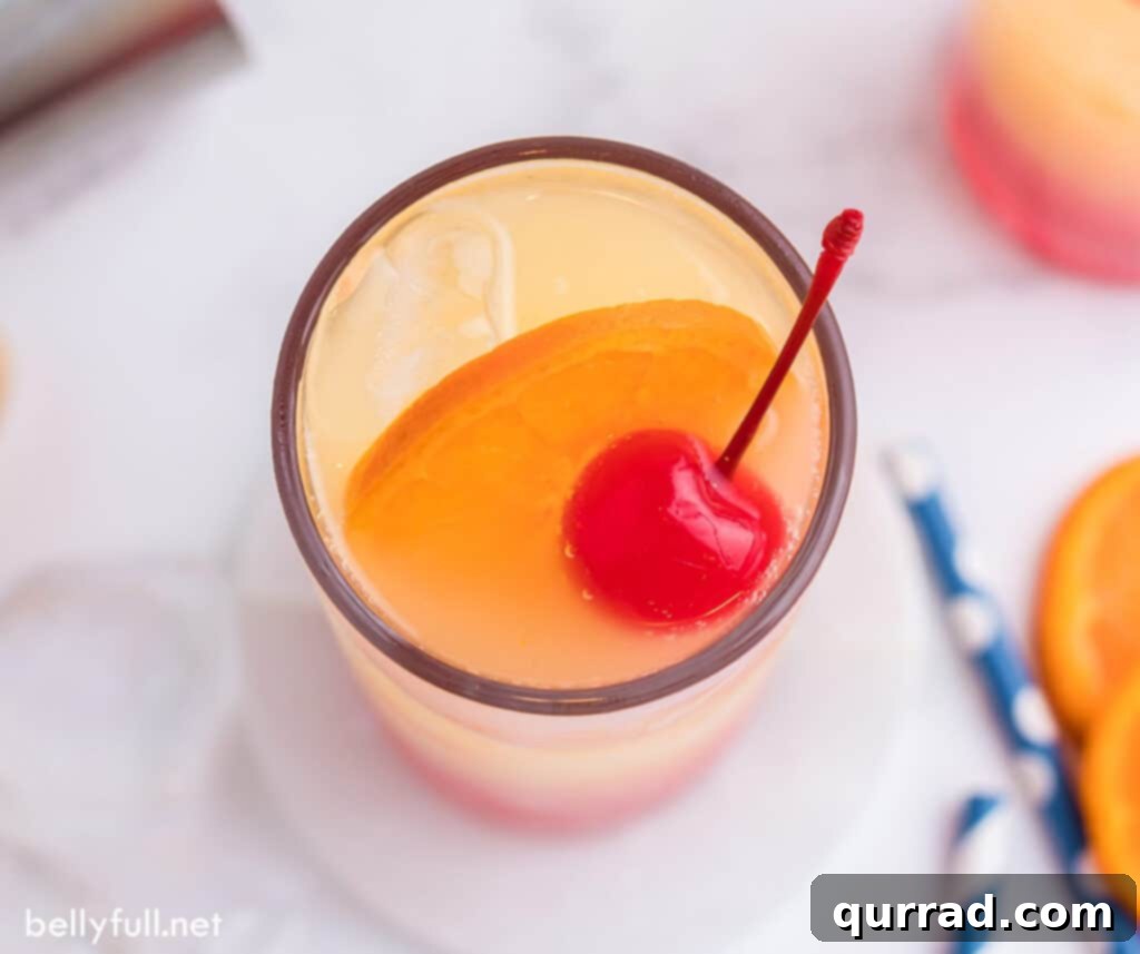 Dawn's Golden Kiss 5 Overhead view of a Tequila Sunrise cocktail with an orange slice and cherry garnish