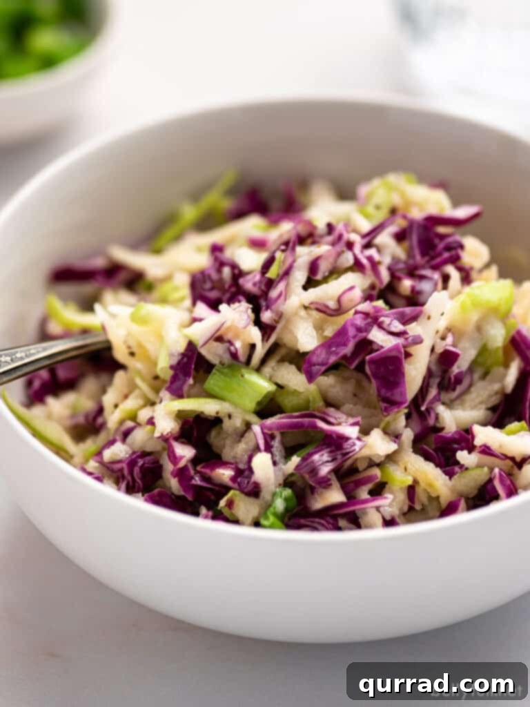 Crimson Cabbage Crunch 3 A close-up shot of a bowl full of vibrant red cabbage and apple coleslaw, showcasing its texture and color.