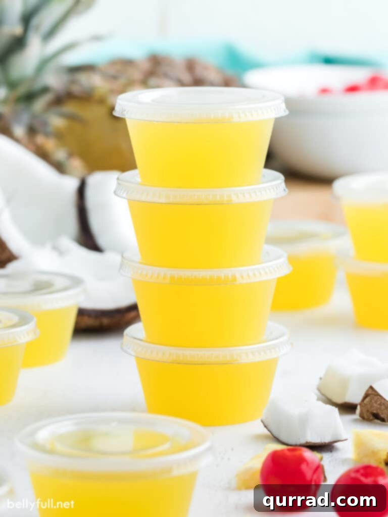 Pineapple Coconut Rum Jellies 3 A stack of yellow jello shot cups with lids, ready for the refrigerator or transportation.
