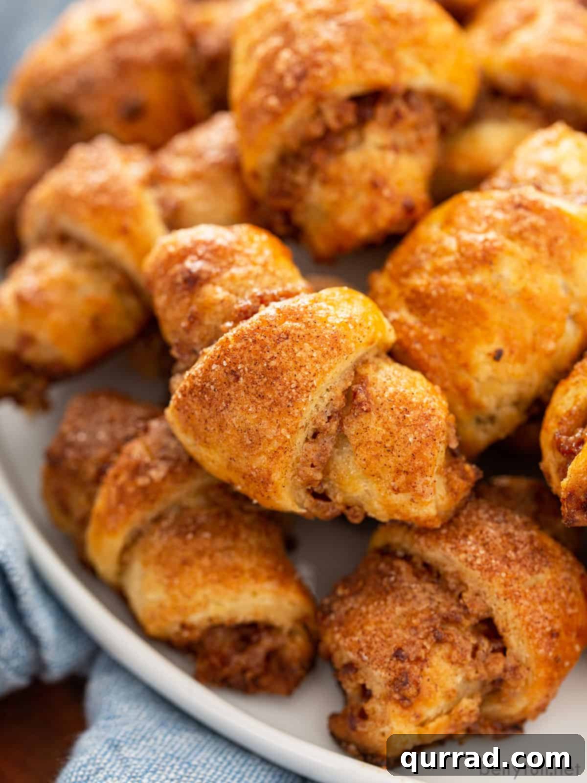 A collection of golden-brown Rugelach cookies arranged on a pristine white tray, showcasing their flaky texture and crescent shape.
