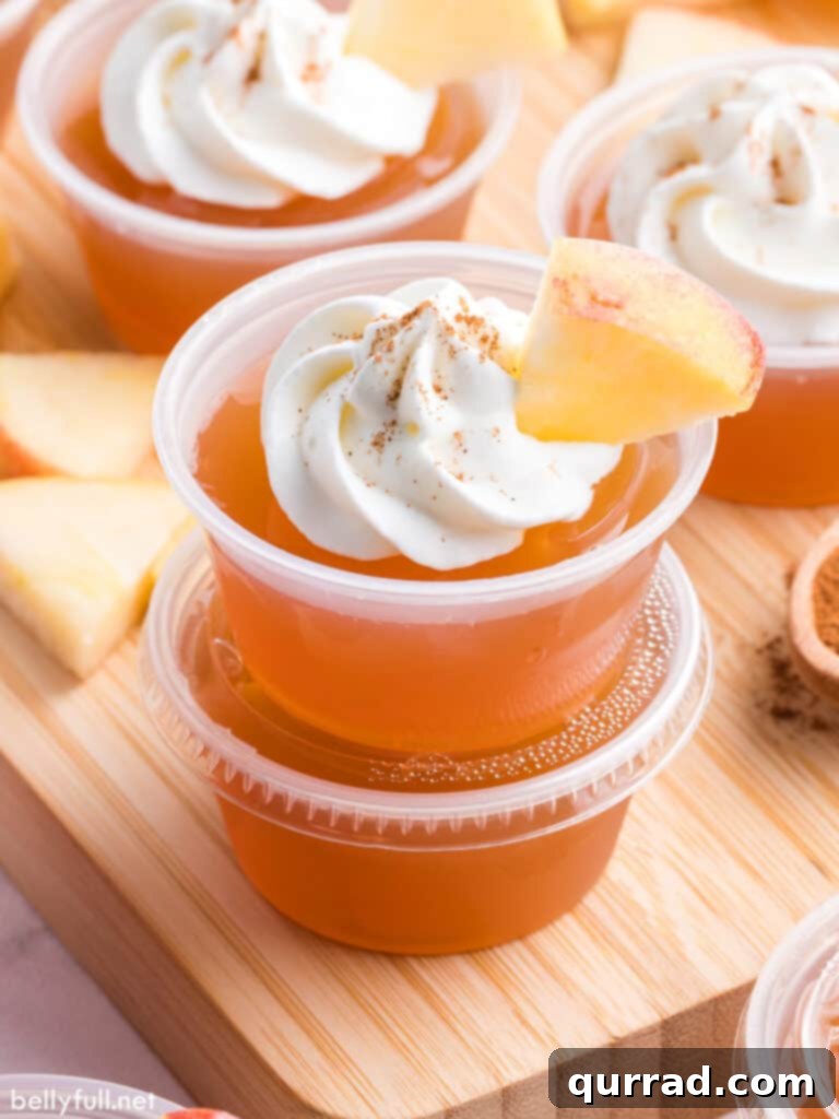 Two stacked apple pie jello shots with whipped cream and cinnamon garnish