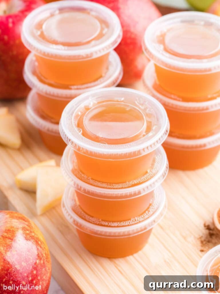 Boozy Apple Pie Jellies 3 Stack of three apple pie jello shots on a rustic wood board, garnished with whipped cream and cinnamon