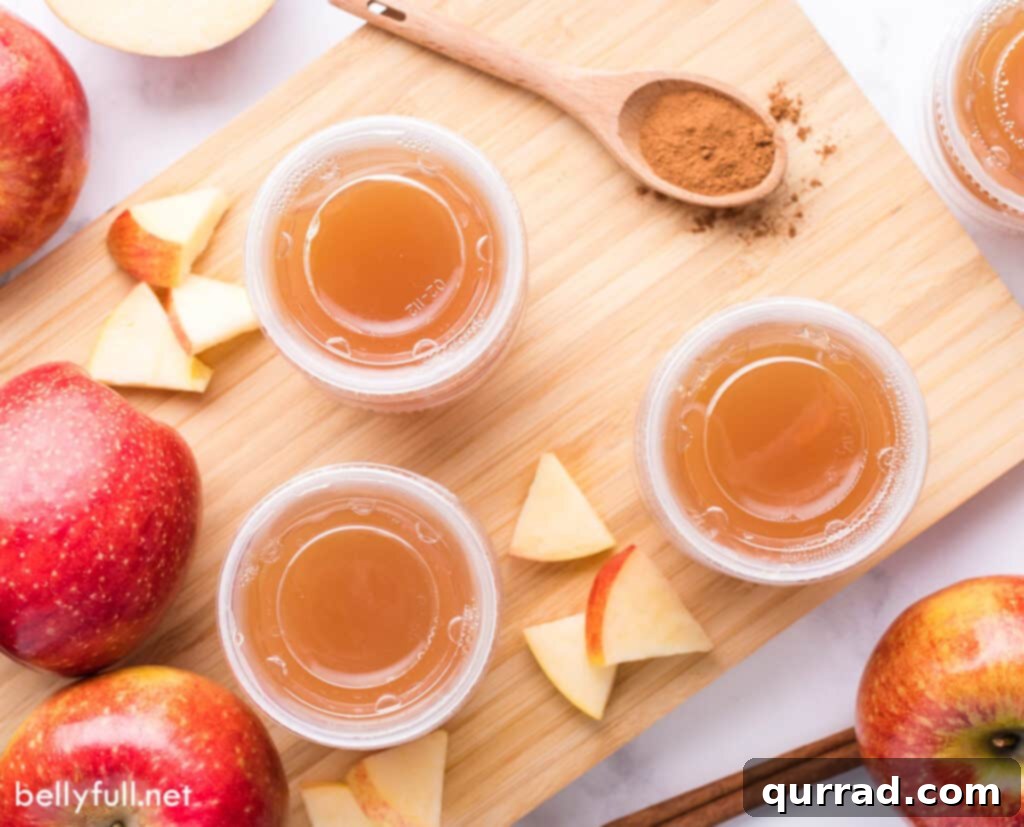 Boozy Apple Pie Jellies 5 Apple pie shots on a wood countertop, with small apple wedges in the center as garnish