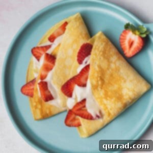 Berry Kissed Crepes 3 overhead crepes on plate with cream filling and sliced strawberries