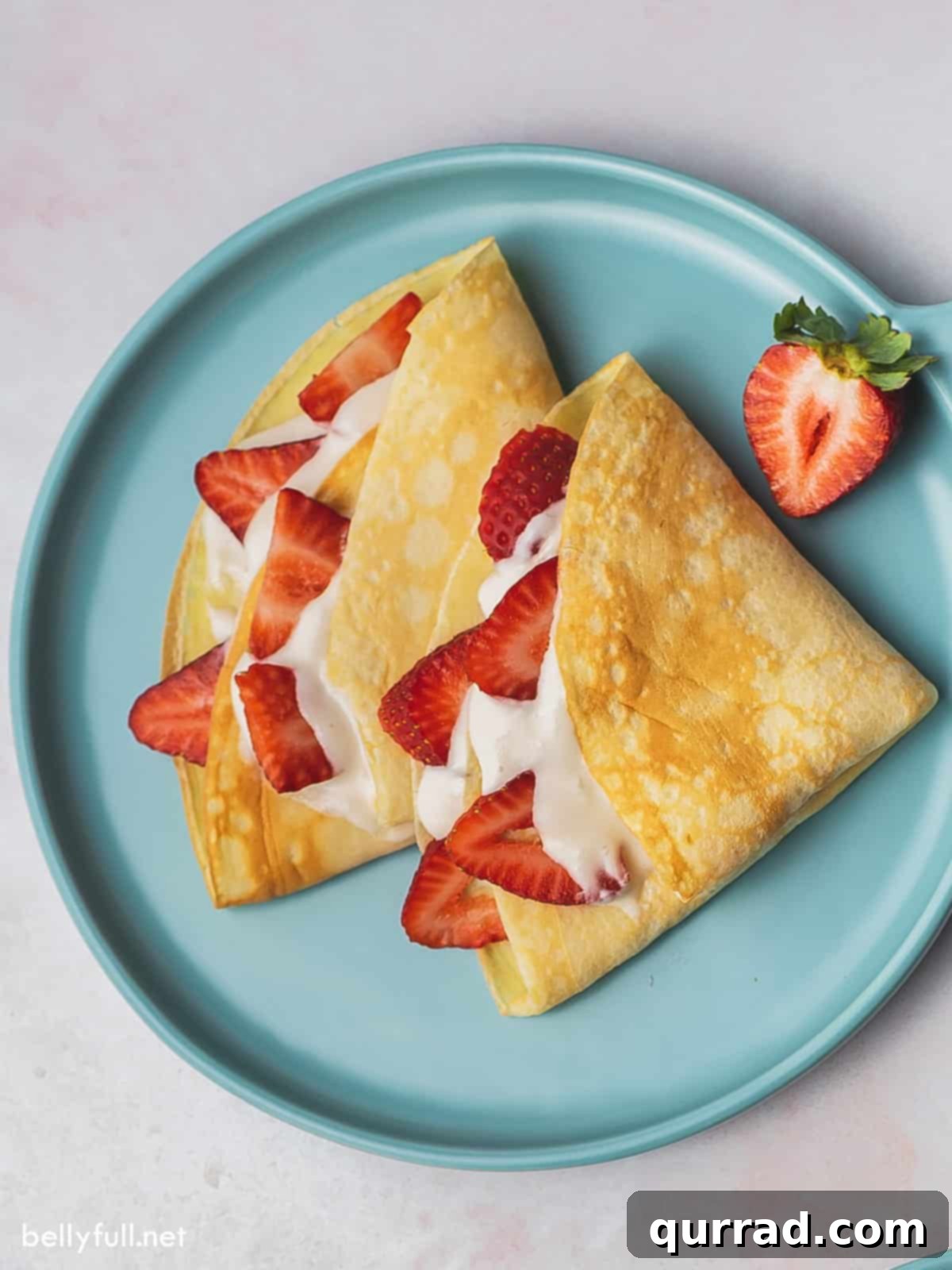 Berry Kissed Crepes 5 overhead crepes on plate with cream filling and sliced strawberries