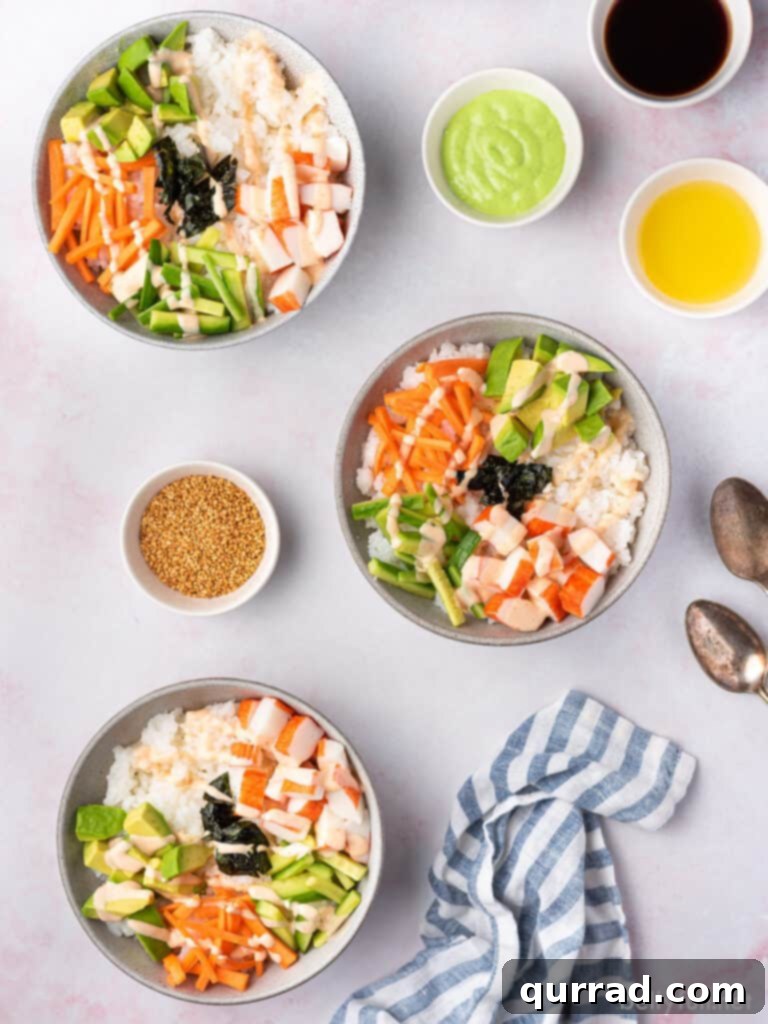 Deconstructed California Roll Bowls 3 Overhead view of three colorful sushi bowls, each featuring sushi rice, carrots, cucumber, avocado, and crab meat