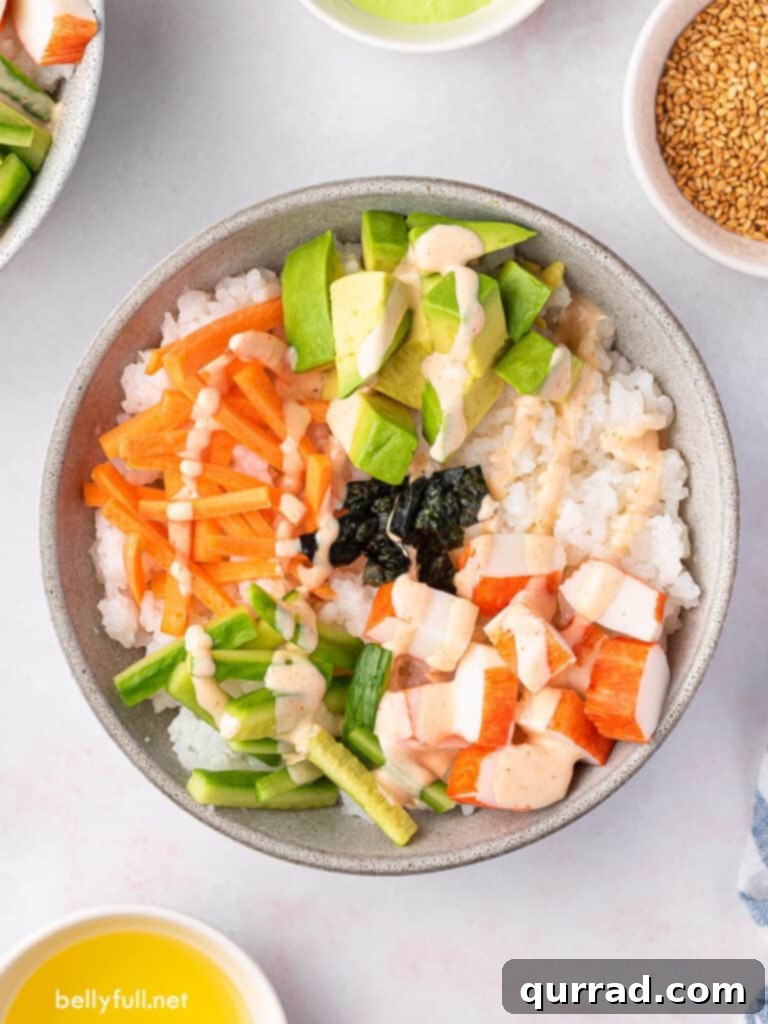 Deconstructed California Roll Bowls 4 Overhead view of a colorful sushi bowl filled with sushi rice, carrots, cucumber, avocado, and imitation crab