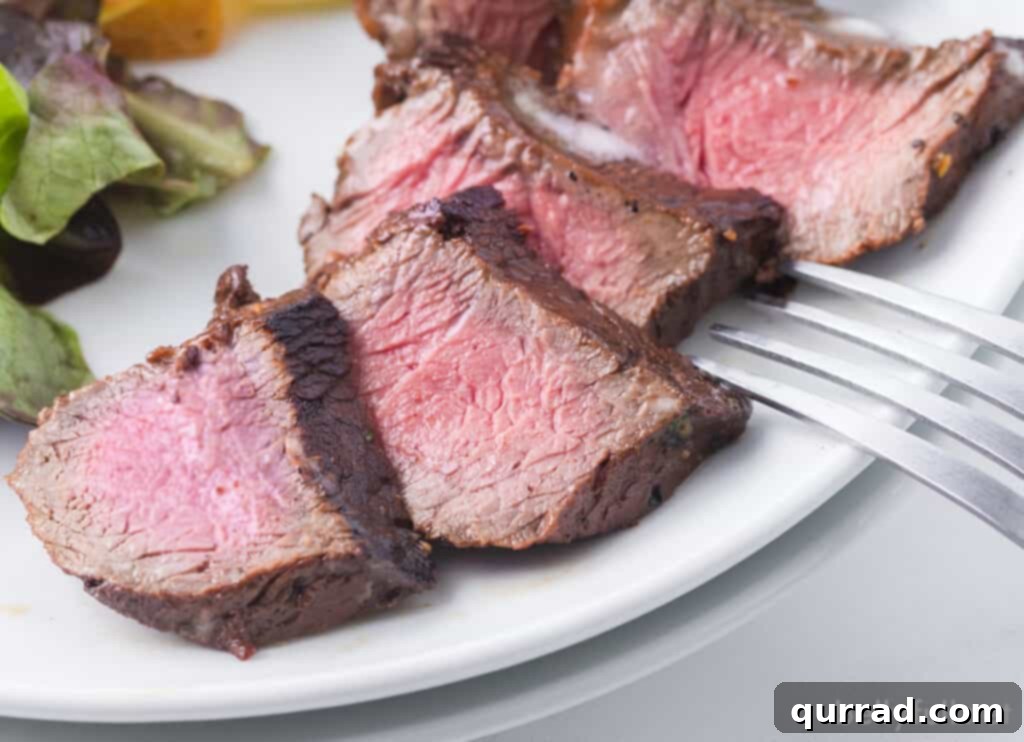 close up sliced steak in easy steak marinade on a plate, garnished with butter and parsley