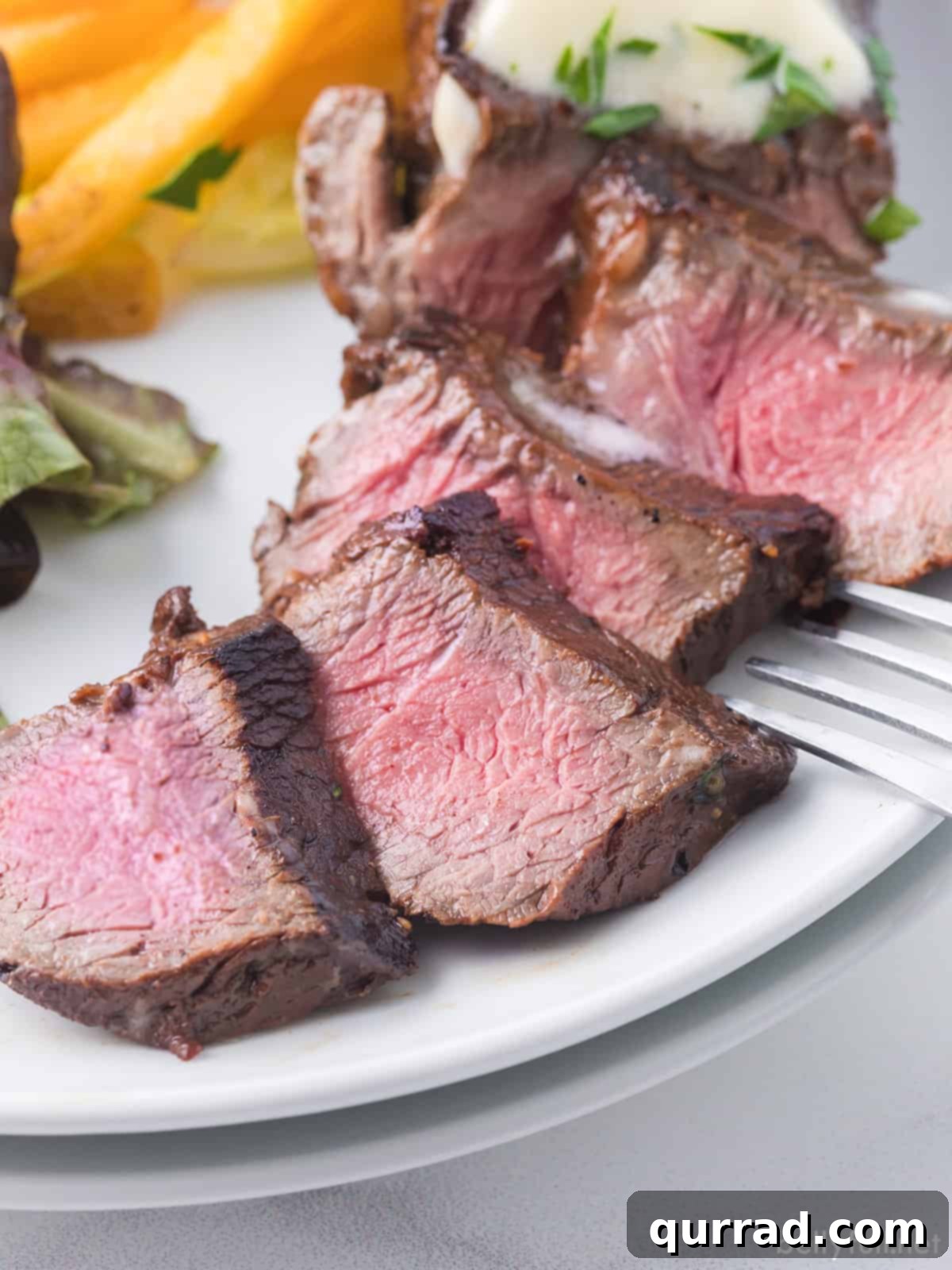 Slices of steak in easy steak marinade on a plate with French fries and chopped parsley