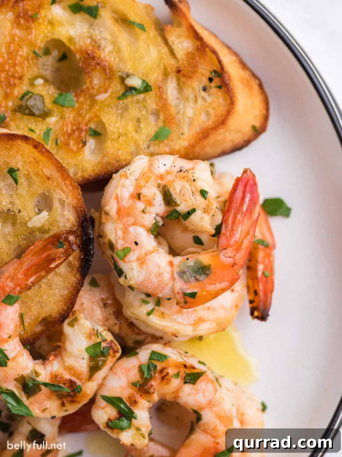 Flame-Kissed Shrimp Scampi 2 A close up of grilled shrimp scampi and baguette slices on a plate