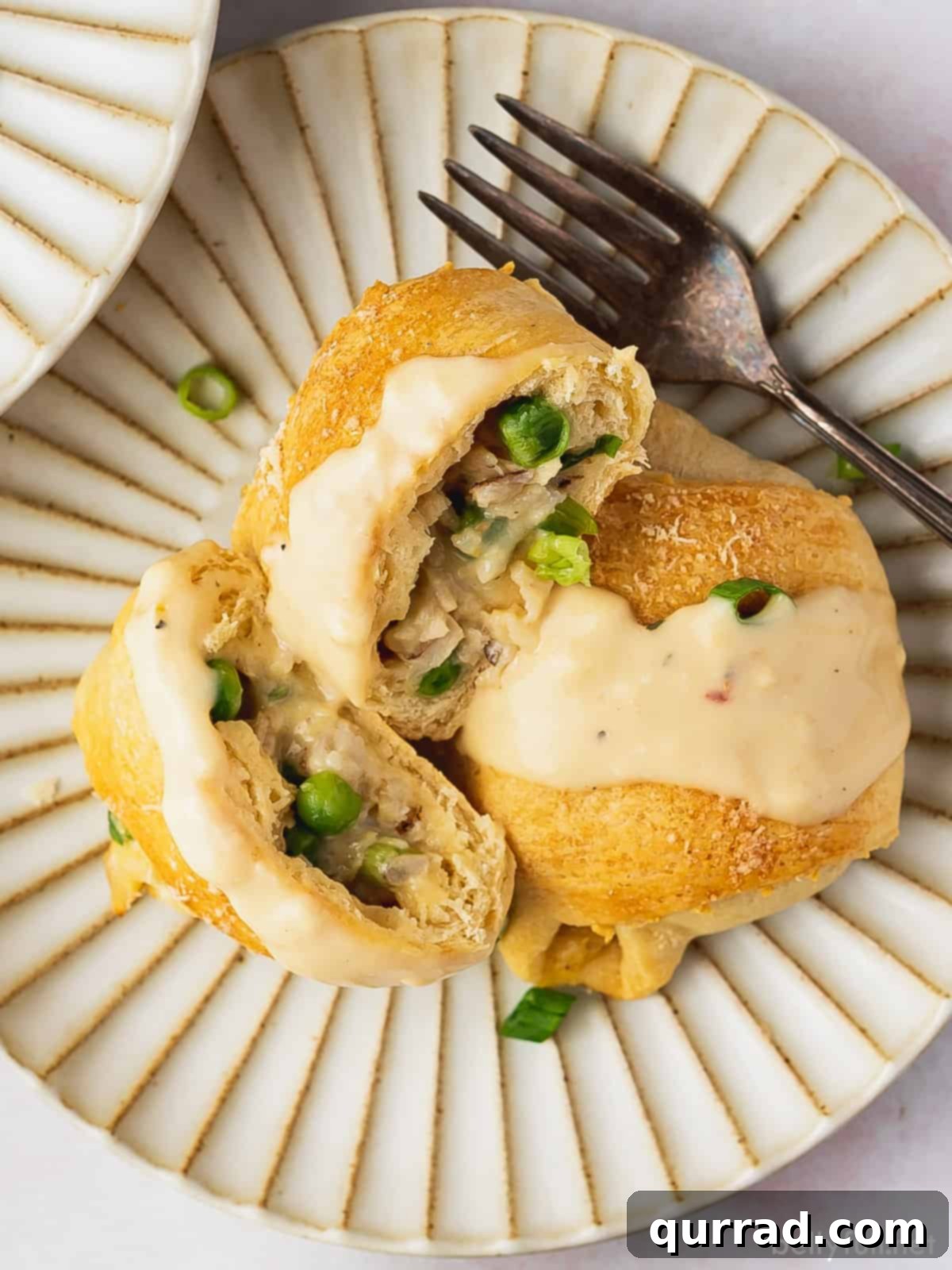 An overhead shot of three chicken crescent roll ups generously coated in gravy, highlighting the inviting textures and golden crusts.