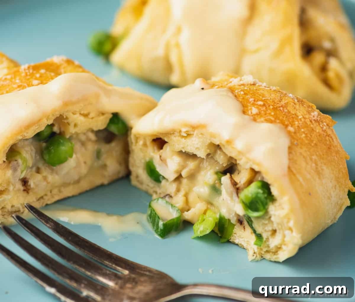 A chicken pot pie crescent roll up sliced in half, revealing the rich, creamy chicken and vegetable filling inside.