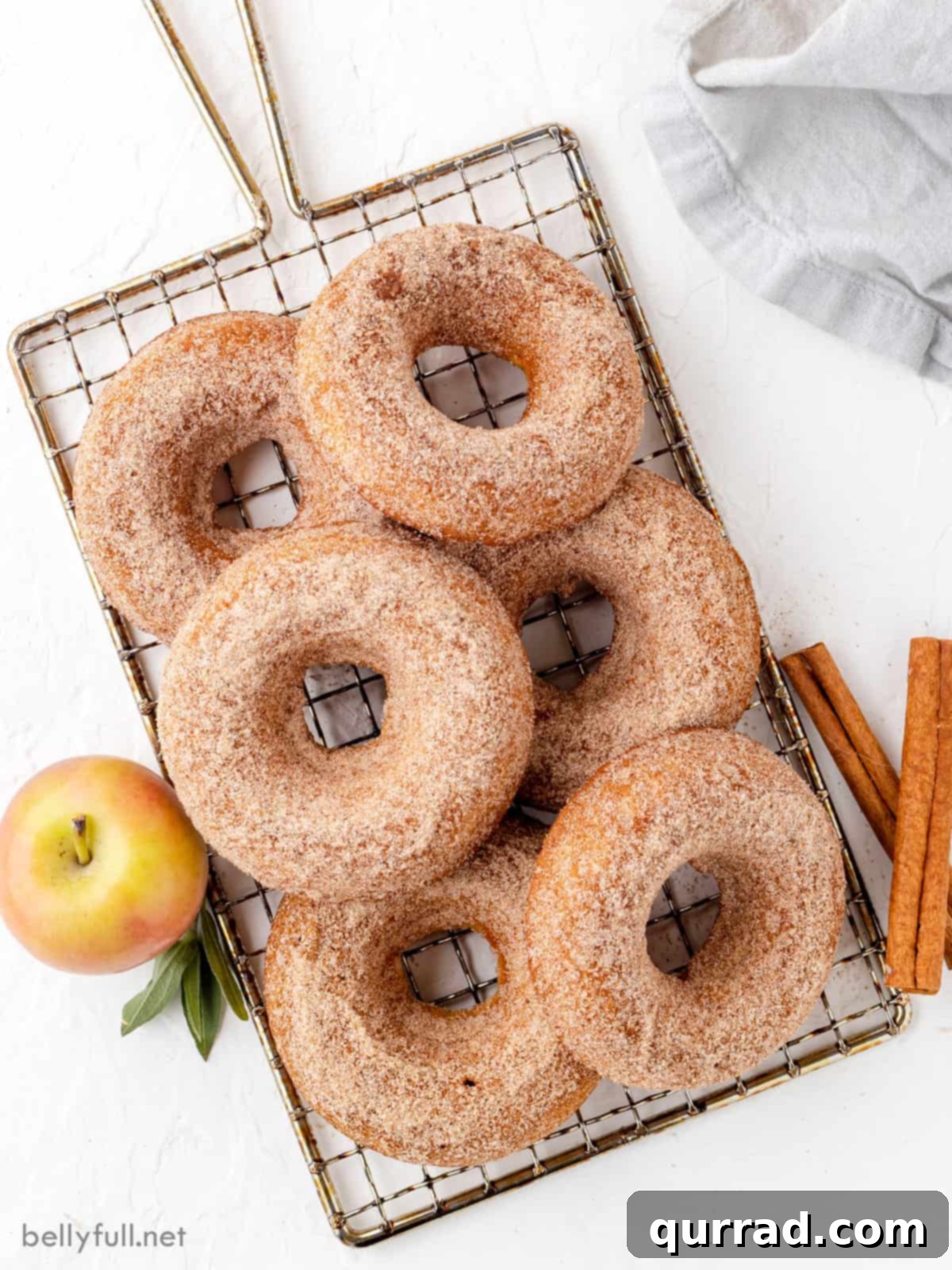 Baked apple cider donuts dipped in cinnamon sugar on a wire rack