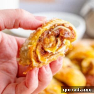 A hand holding a piece of pumpkin pull-apart roll, showing the flaky pastry and delicious filling