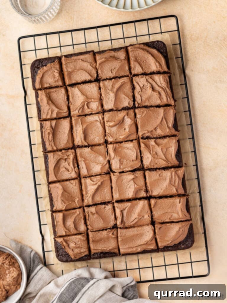 Velvet Chocolate Mayonnaise Cake 3 Overhead shot of a rectangular frosted chocolate mayonnaise cake, with several slices already cut, resting on a wire rack.