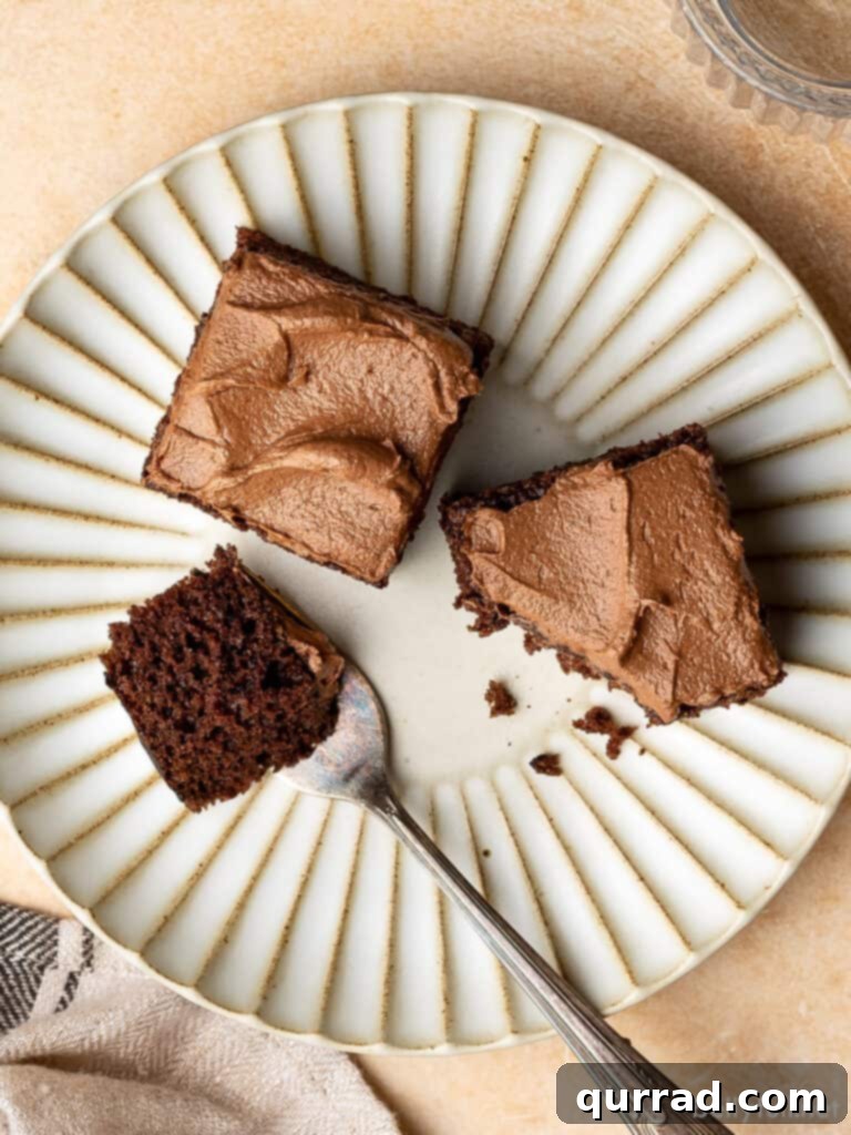 Velvet Chocolate Mayonnaise Cake 4 Two sliced squares of chocolate mayonnaise cake, frosted and served on a white plate with a fork.