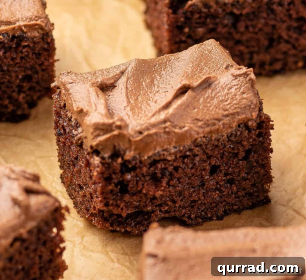 Velvet Chocolate Mayonnaise Cake 5 Close-up shot of a slice of frosted chocolate mayonnaise cake on brown parchment paper, showing the moist crumb.