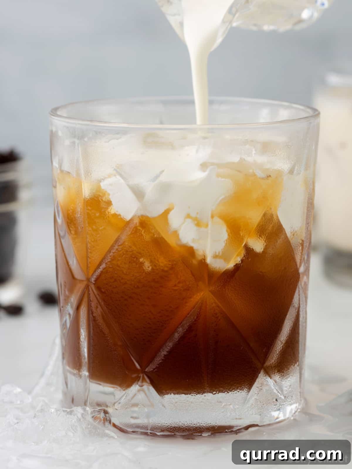 Velvet Nightcap 3 Heavy cream being gently poured into a glass containing vodka and coffee liqueur, forming the signature swirl of a White Russian cocktail.