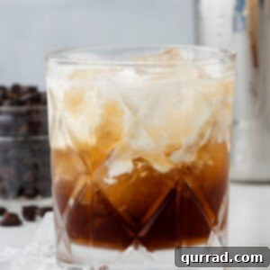A slightly swirled White Russian cocktail in a lowball glass.