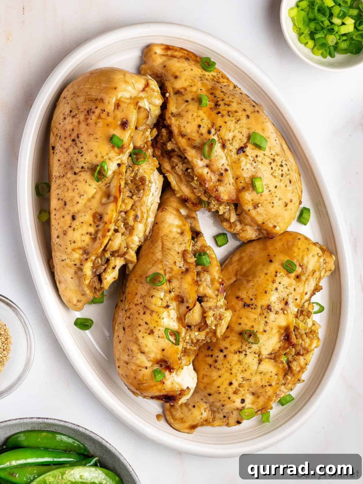 Fragrant Asian Rice Stuffed Chicken 3 Four golden-brown Asian rice stuffed chicken breasts arranged on a white serving platter, garnished with fresh herbs, ready for a family meal.