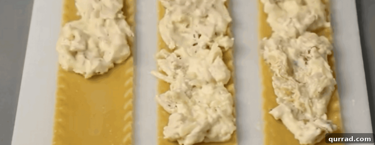 Spreading the chicken filling over the lasagna noodles. 