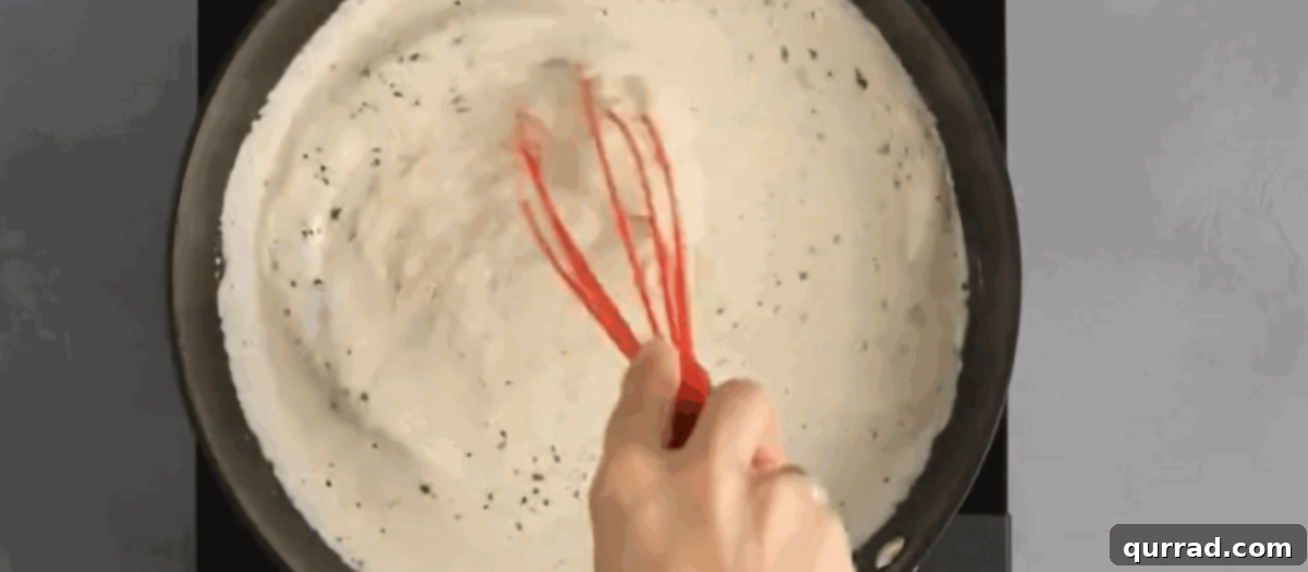 Adding Parmesan cheese to the Alfredo sauce. 