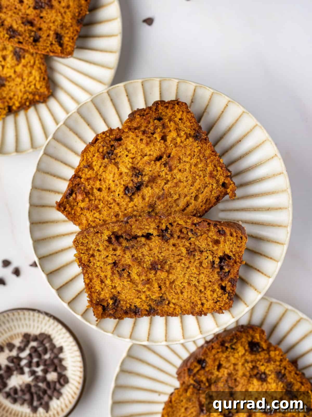 Harvest Pumpkin Chocolate Chip Loaf 2 Overhead view of two slices of pumpkin chocolate chip bread on a white plate, showcasing the moist interior and abundance of chocolate chips.