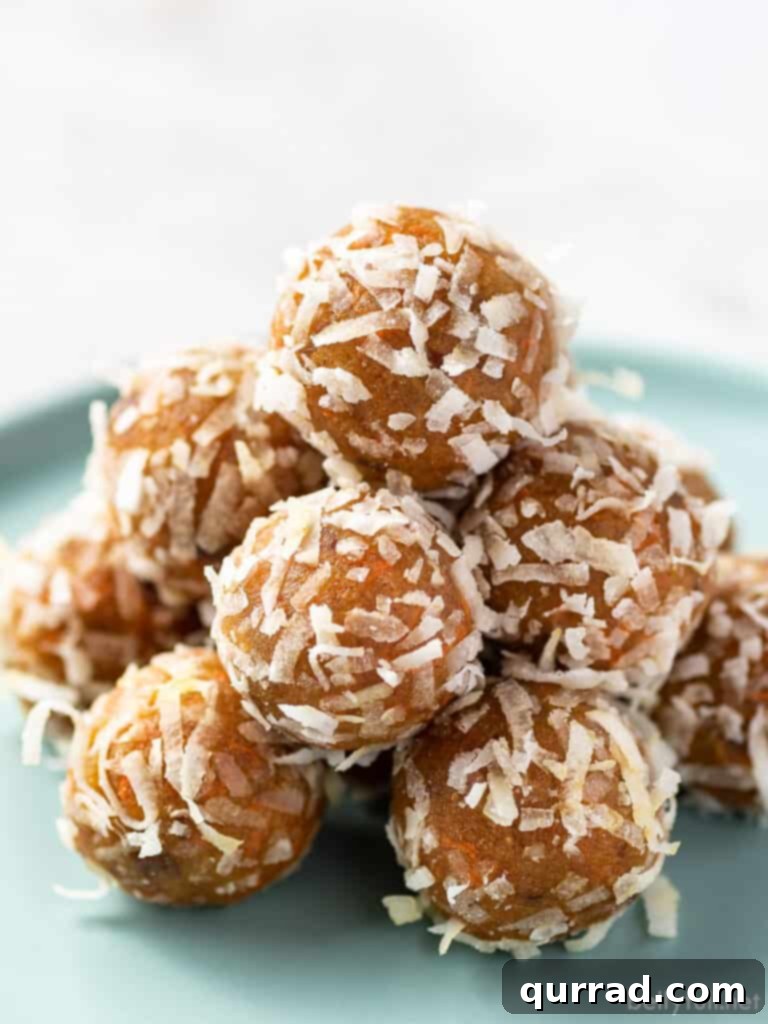 Carrot Cake Bliss Bites 2 Carrot cake energy balls coated in coconut flakes piled on a plate, showcasing their inviting texture and rich color.