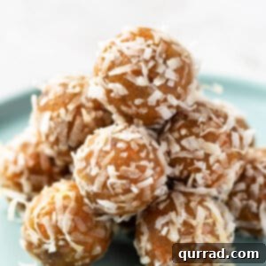 Carrot Cake Bliss Bites 6 carrot cake energy balls coated in coconut flakes piled on a plate