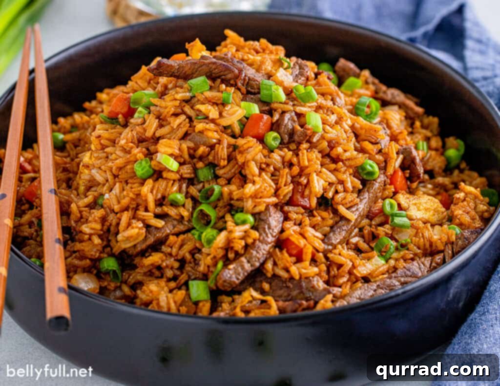 Savory Beef Fried Rice 4 Flavorful fried rice with beef, scrambled eggs, and colorful vegetables served in a black bowl with chopsticks.