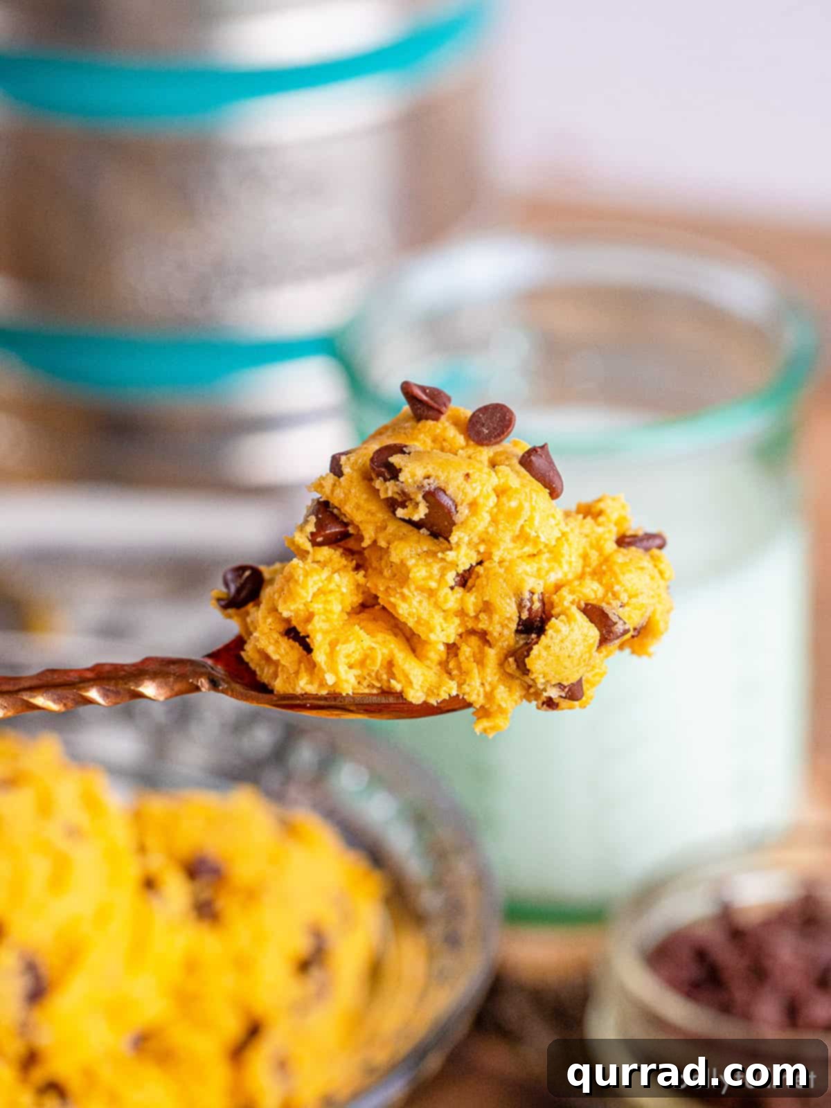 A spoonful of pumpkin edible cookie dough being lifted from a bowl