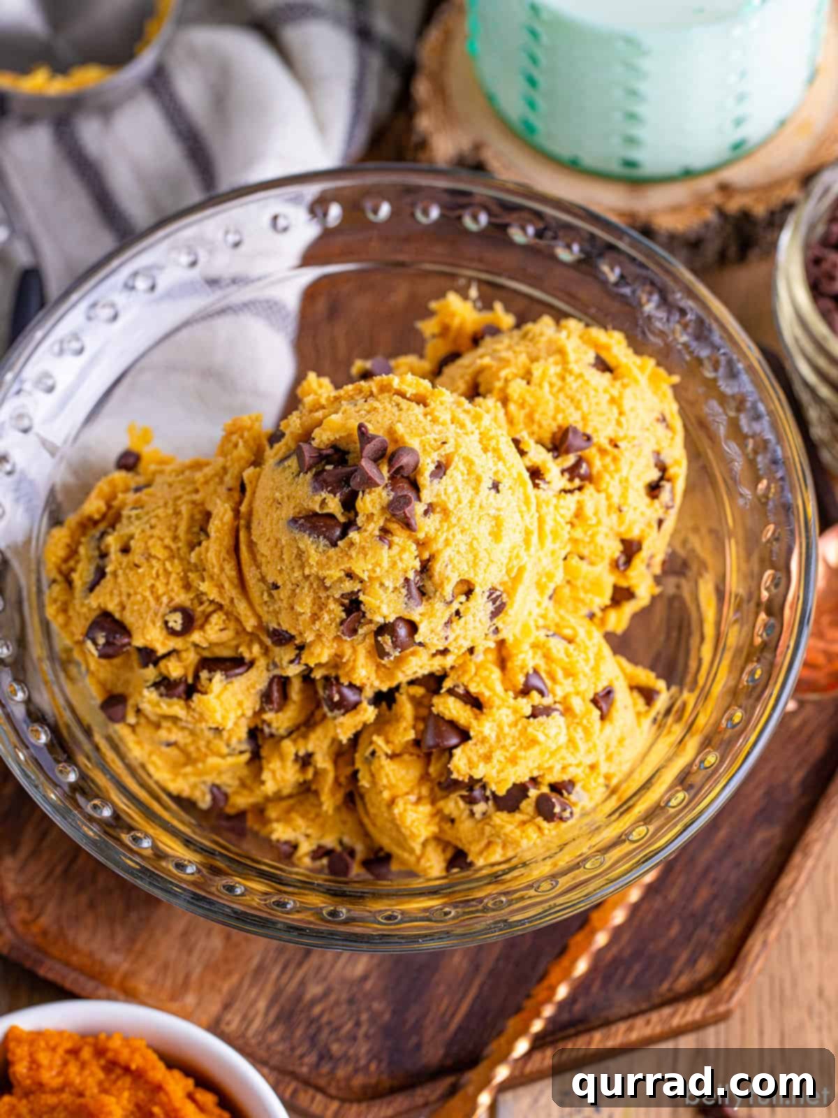 Pumpkin chocolate chip edible cookie dough in a bowl, with a spoon digging in