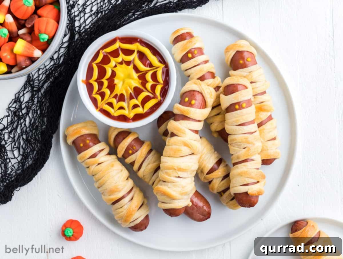 Frank-N-Mummies 5 A festive plate of Halloween mummy hot dogs with a bowl of spiderweb sauce, perfect for a party
