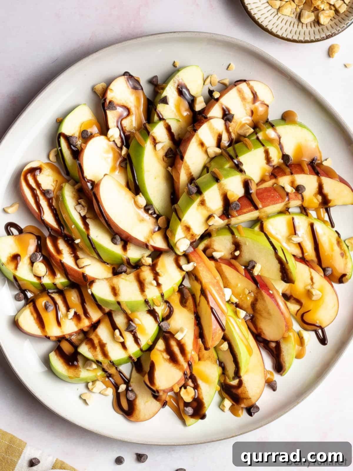 Overhead view of apple nachos, a colorful platter of sliced apples with caramel and chocolate drizzles, sprinkled with various toppings.