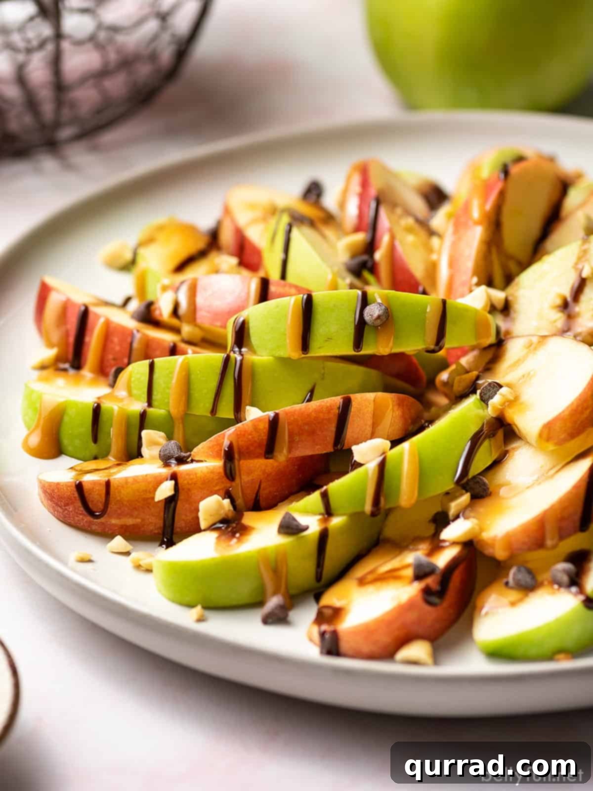 A vibrant plate of caramel apple nachos, featuring sliced apples generously coated with hot fudge and caramel sauce, adorned with various delicious toppings.