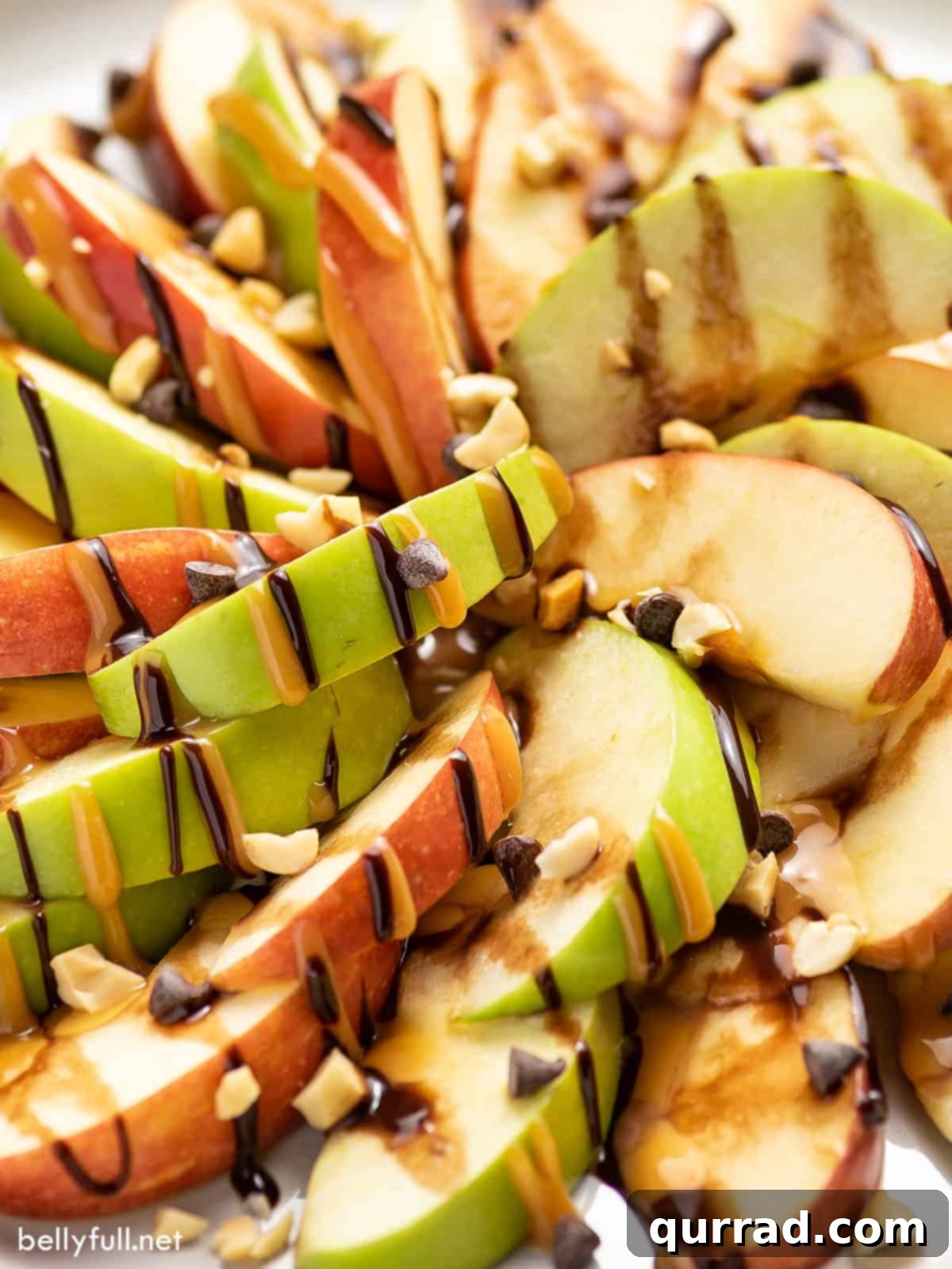 Close-up detail of caramel apple nachos, showcasing the rich hot fudge and caramel sauce drizzles over crisp apple slices, adorned with mini chocolate chips.