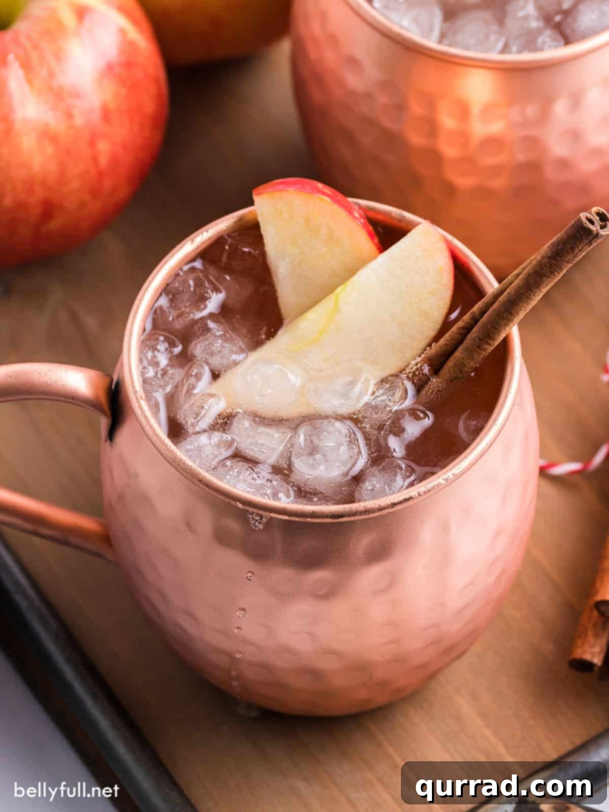 Crisp Apple Mule 2 An inviting Apple Cider Moscow Mule, garnished with vibrant apple slices and a fragrant cinnamon stick, ready to be enjoyed.