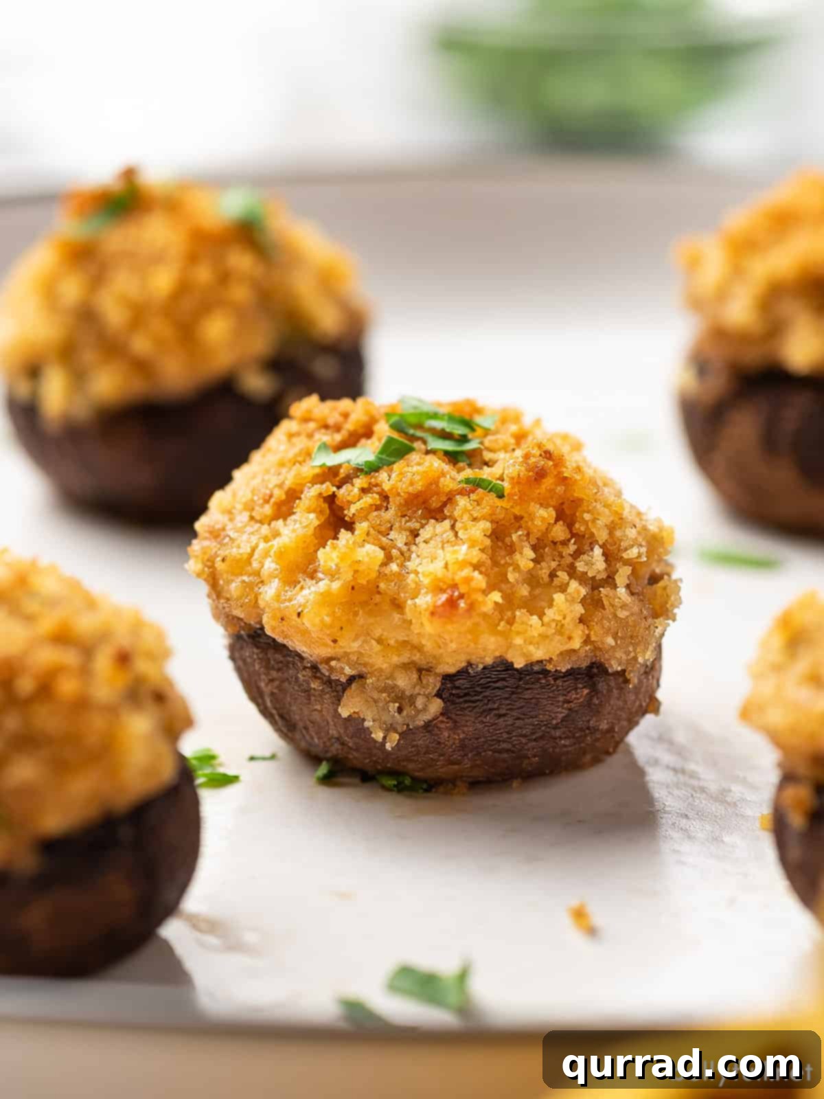 Velvet Crab Stuffed Mushrooms 4 Crab stuffed mushrooms on a white serving plate, garnished with herbs
