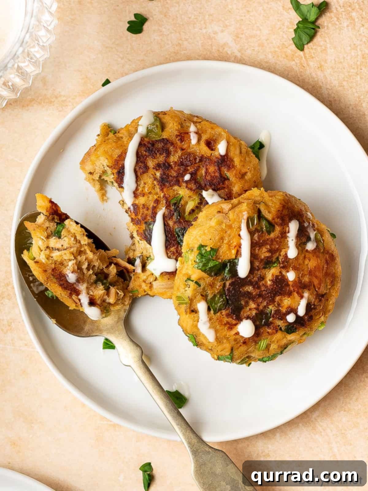 Savory Salmon Cakes 5 Two salmon patties on a white plate with a fork holding a bite of one