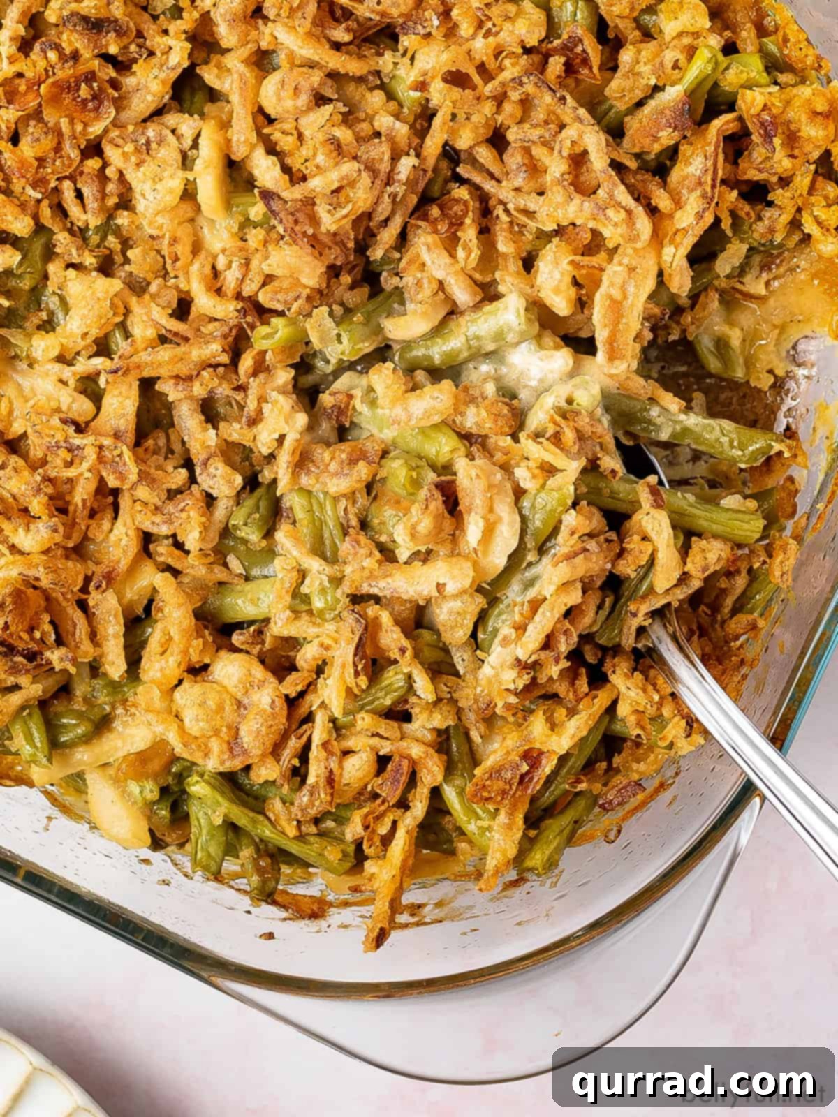 Comforting Green Bean Bake 2 A spoon in a baking dish of green bean casserole, ready to be served.