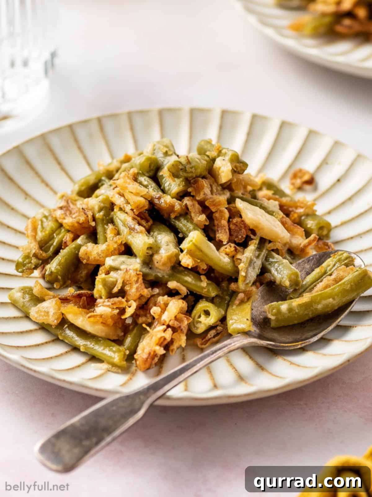 Comforting Green Bean Bake 3 A plate of green bean casserole with a fork, showing its creamy texture and crispy topping.