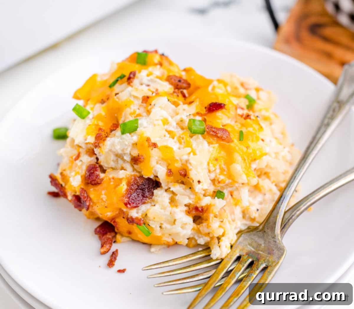 Golden Cheesy Potato Bake 5 A generous serving of cheesy hash brown potatoes on a plate, garnished with fresh green herbs.