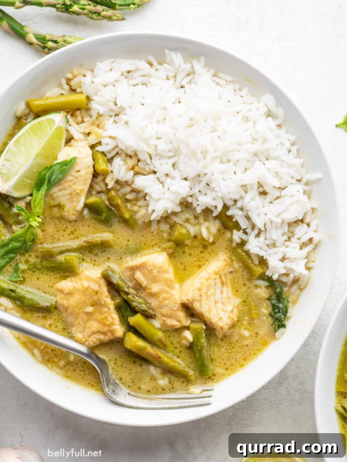 Emerald Green Thai Curry 2 A bowl of vibrant Thai green curry with tender fish fillets and a side of aromatic jasmine rice.