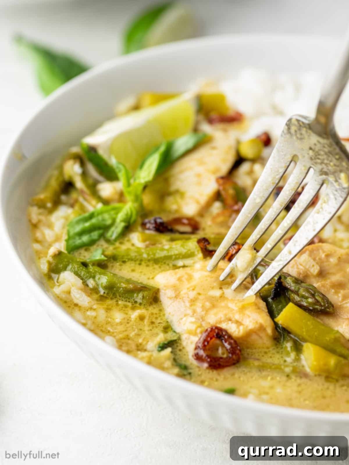 Emerald Green Thai Curry 4 A close-up view of Thai green curry with fish, showing the flaky texture of the fish and a fork resting in the bowl.