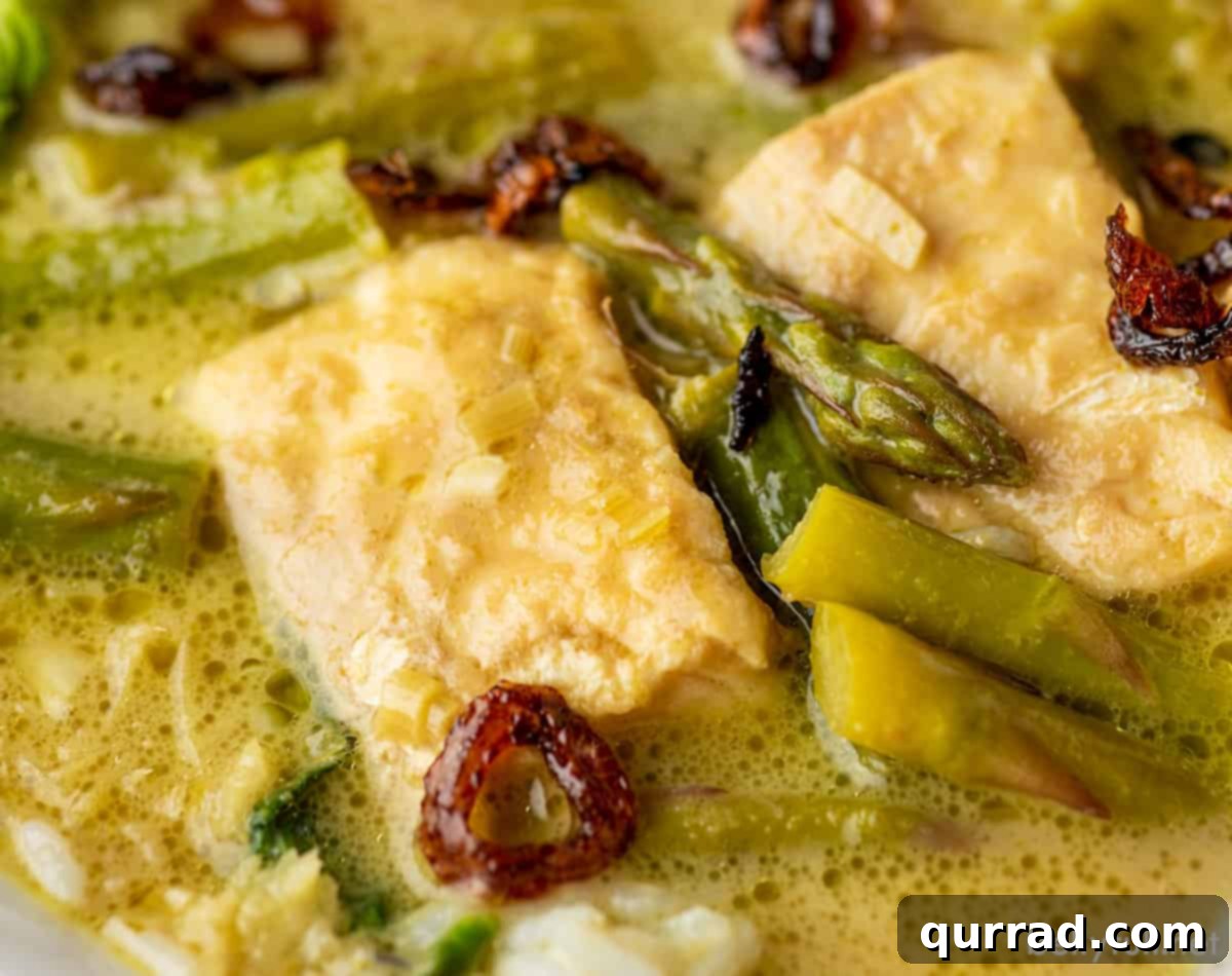 Emerald Green Thai Curry 5 A close-up shot of the Thai green curry with fish, showcasing the textures of the ingredients within the vibrant green sauce.