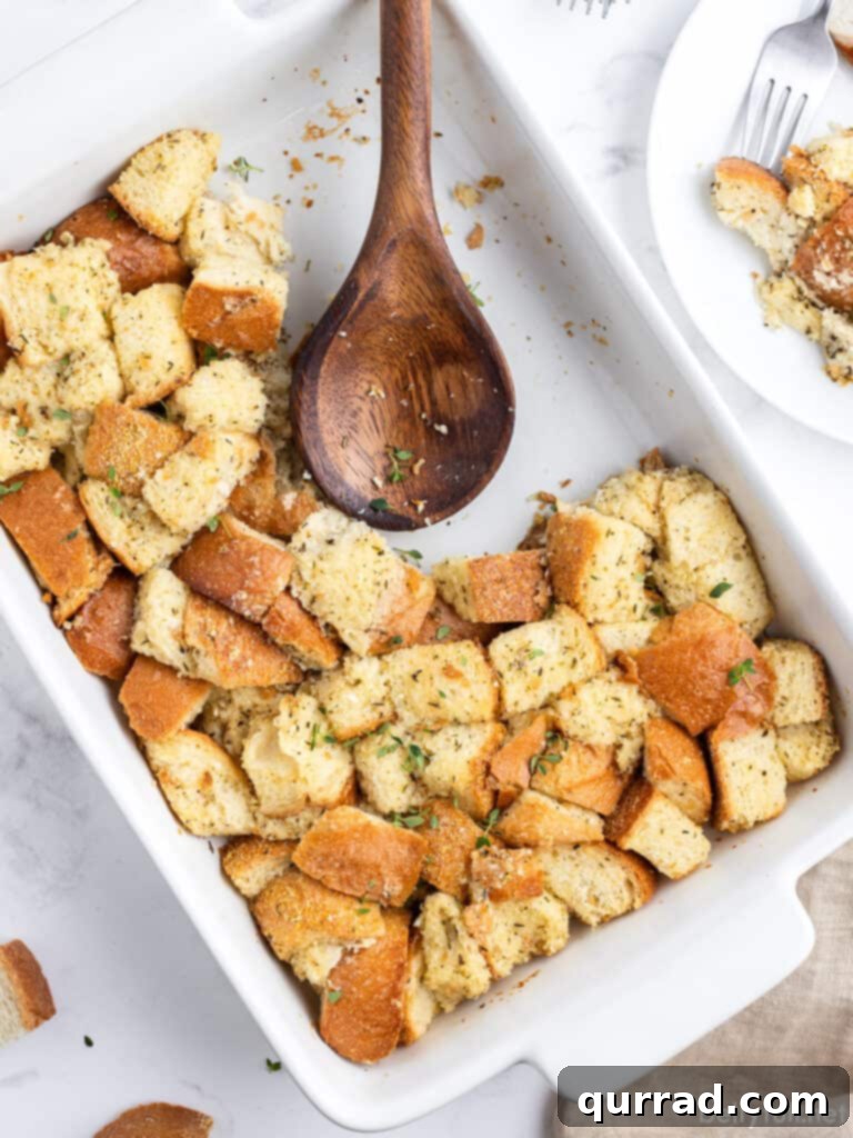 Nana's Simple Stuffing Recipe 4 Stuffing served in a casserole dish with a wooden spoon, showcasing its inviting texture and golden-brown top.
