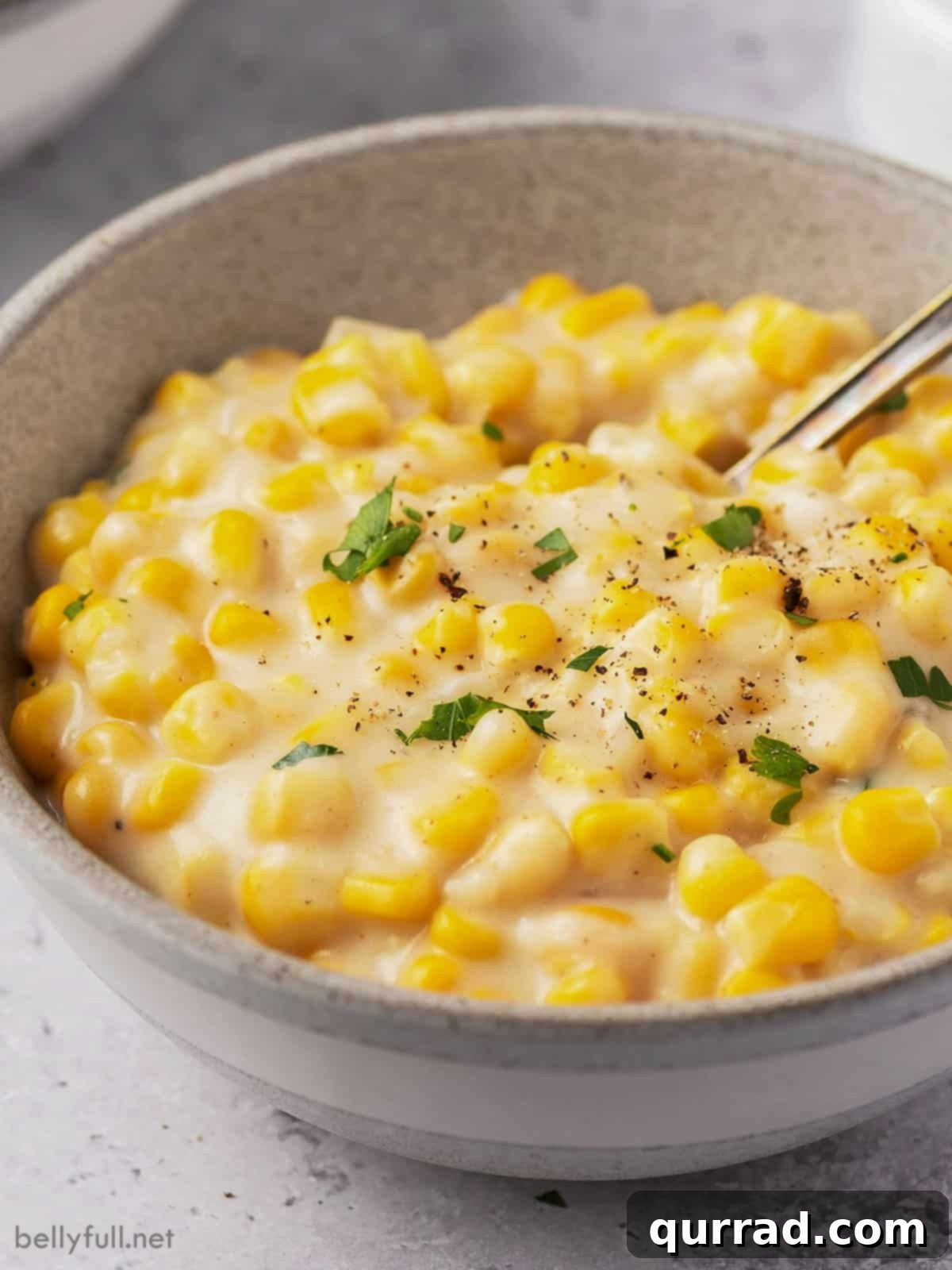 Golden Harvest Cream 7 A bowl of easy creamed corn garnished with fresh parsley and black pepper, ready to eat.