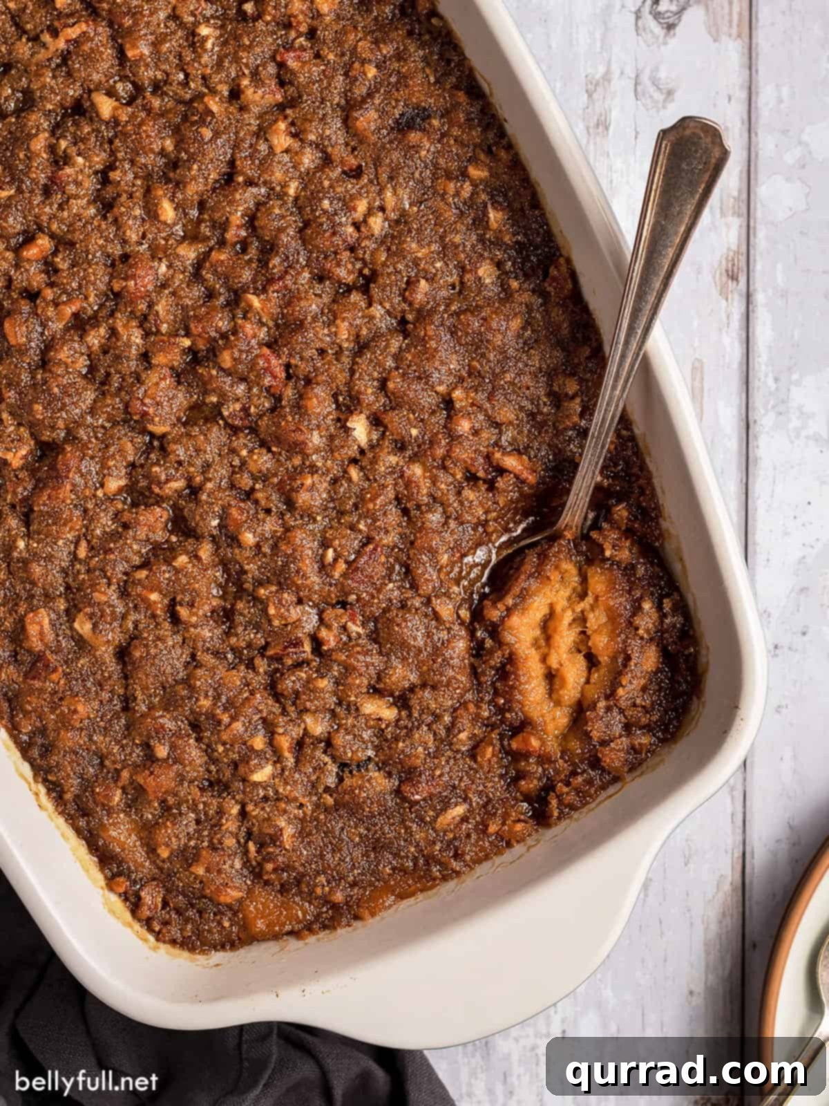 Heavenly Sweet Potato Bake 2 Overhead view of a golden brown sweet potato casserole in a white baking dish, ready to be served with a spoon.