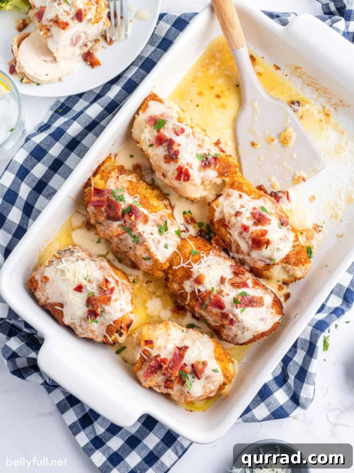 Golden Chicken Ham and Swiss 2 Overhead view of a baking dish of chicken cordon bleu, adorned with Alfredo sauce and crispy bacon.