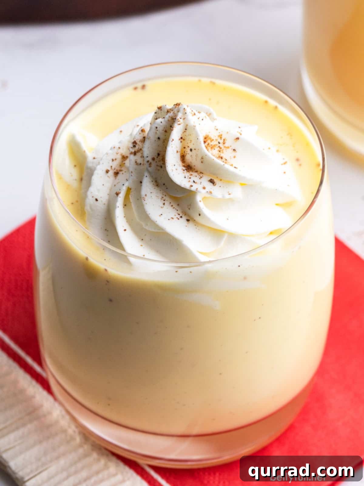 Winter Warmer Eggnog 2 A festive glass of homemade eggnog, garnished with whipped cream and a dusting of nutmeg, ready for holiday enjoyment.